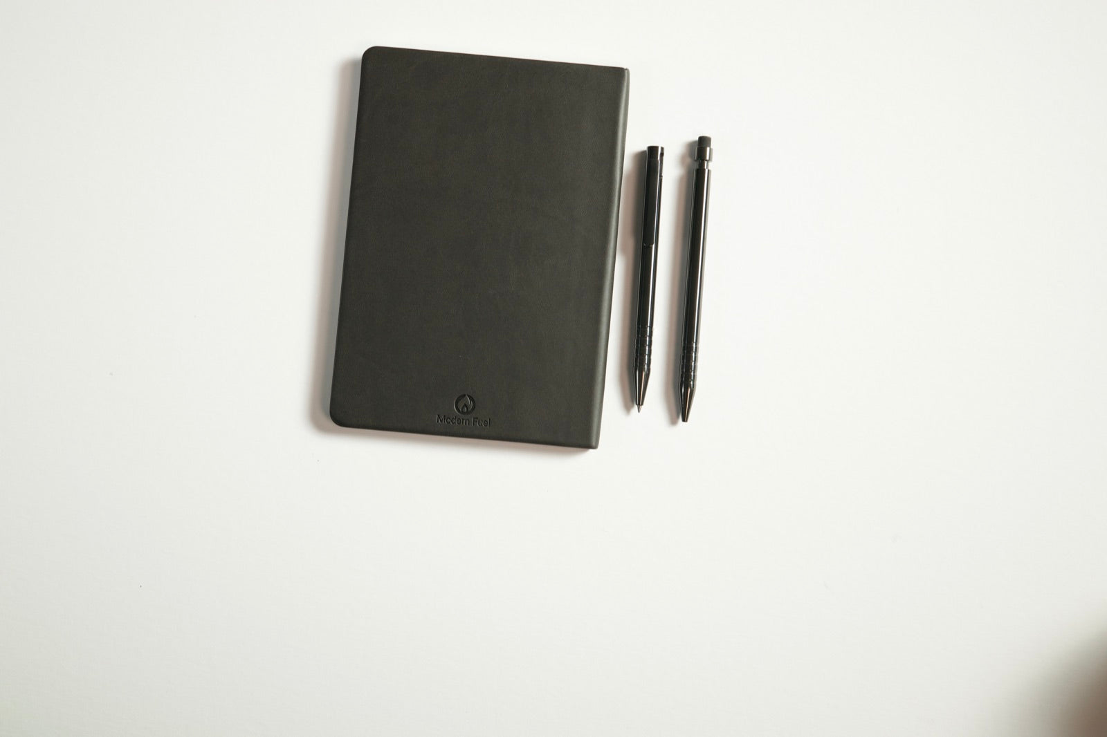 Zirconium Adjustable Bolt Action Pen and Zirconium Click Pencil beside the Modern Fuel notebook